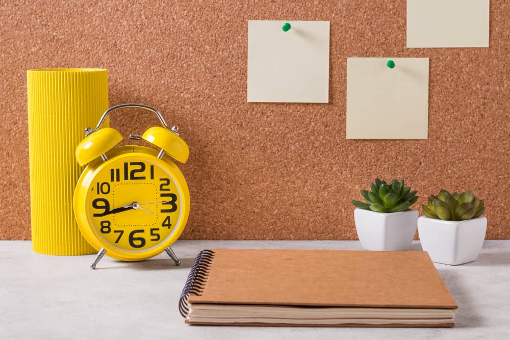 Horloge de bureau jaune sur une table, avec des notes adhésives.