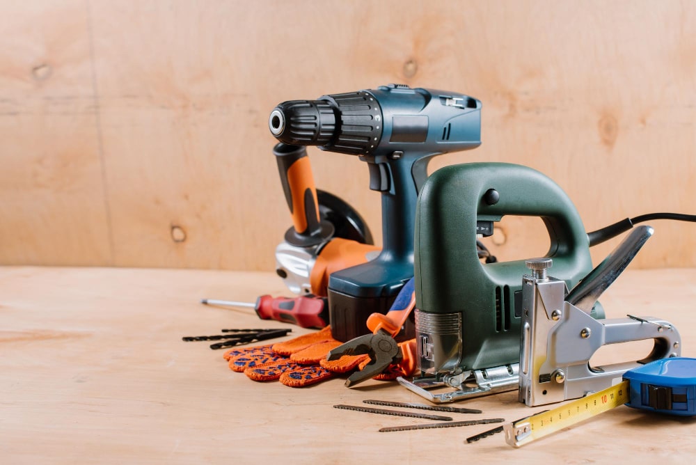 Un ensemble d'outils de bricolage sans fil, incluant une perceuse et une scie sauteuse, posés sur une surface en bois clair