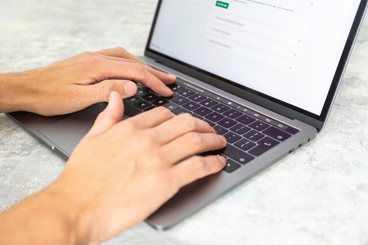 Gros plan sur une personne tapant sur un ordinateur portable pour trouver les meilleurs logiciels IA sur une table grise.