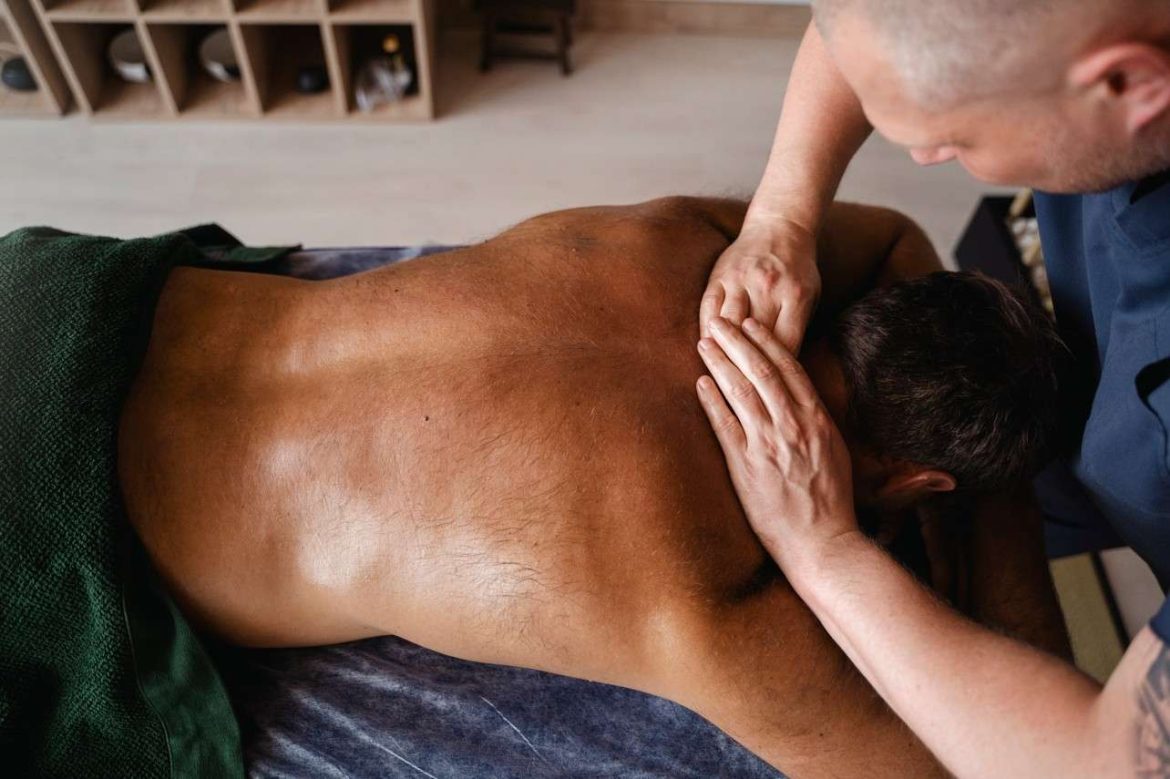 Praticien effectuant des pressions manuelles sur le dos d'un homme pour soulager le mal de dos par un massage thérapeutique.