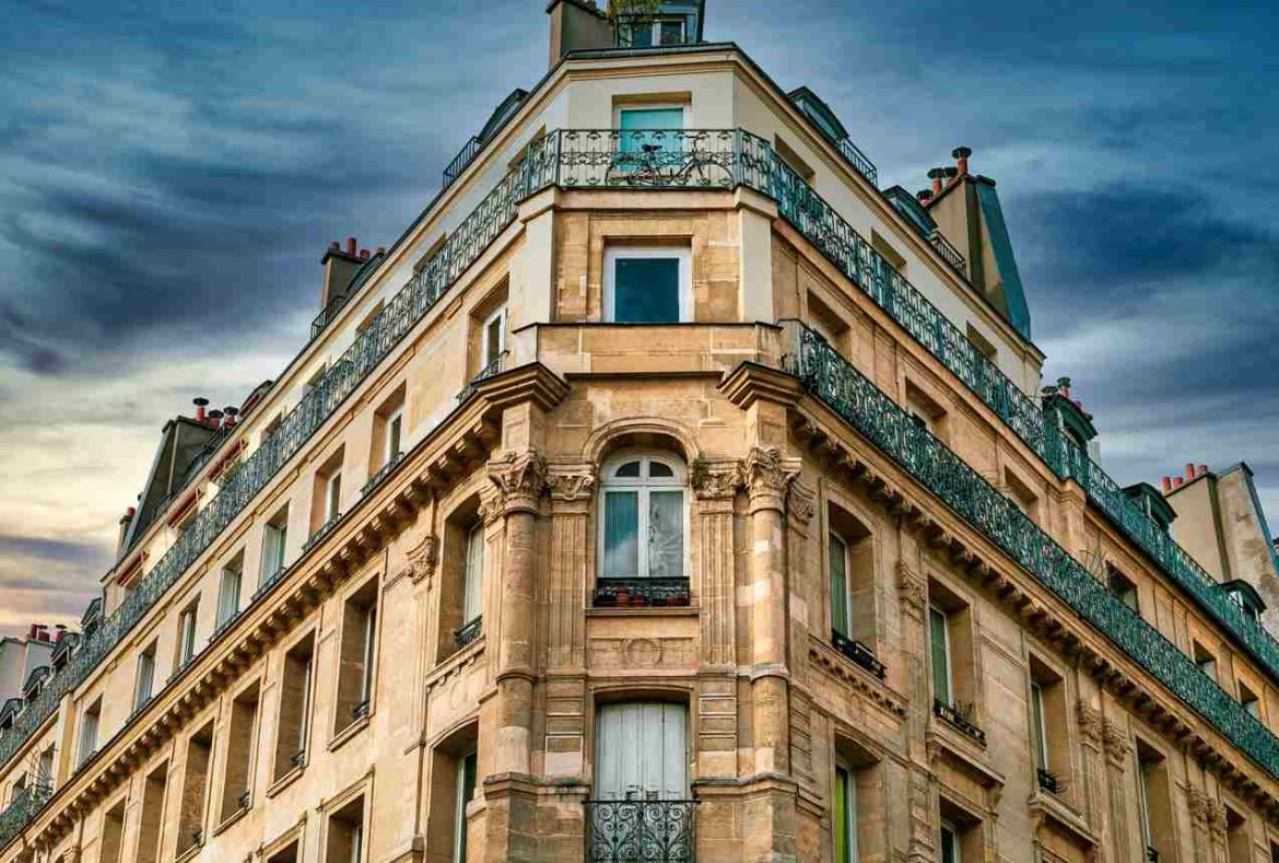 Immeuble haussmannien en pierre à l'architecture classique, idéal pour une adresse de domiciliation d'entreprise à Paris sous un ciel nuageux spectaculaire.